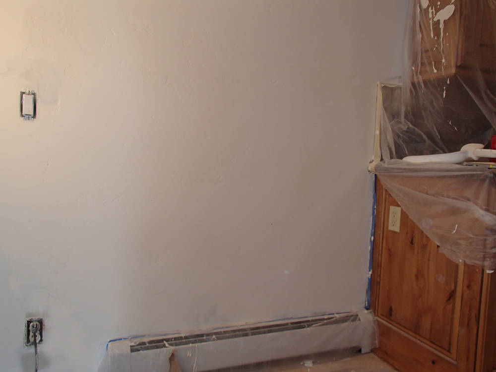 showing a wall once the drywall was repaired and textured ready for primer and paint.