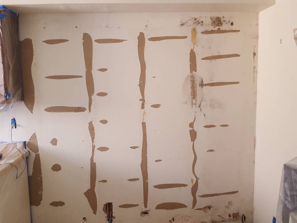 Wall that needs drywall repair after some mirrors were removed from it.