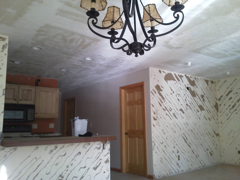 Showing a condominium after popcorn ceiling removal from the ceiling and wood removal from the walls.