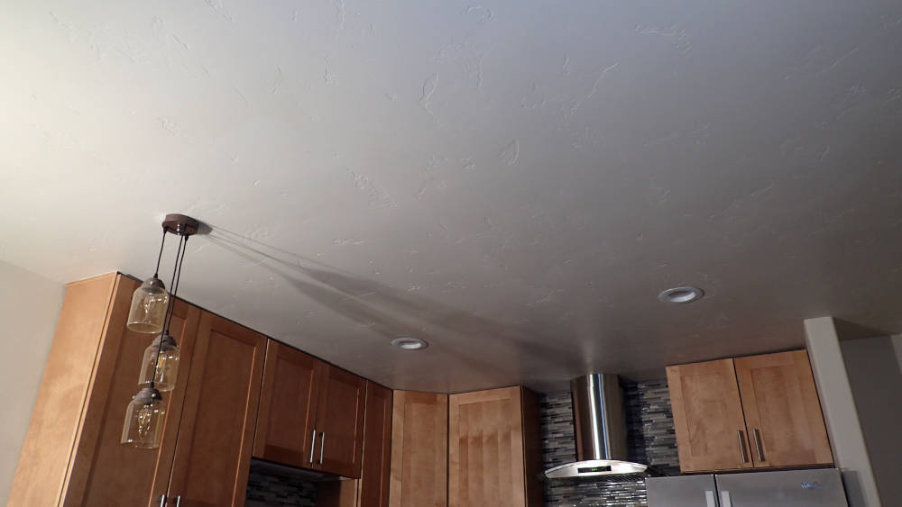Kitchen area in a condominium in Vail, Colorado re-textured from an orange peel to a skip trowel drywall texture, primed and painted.