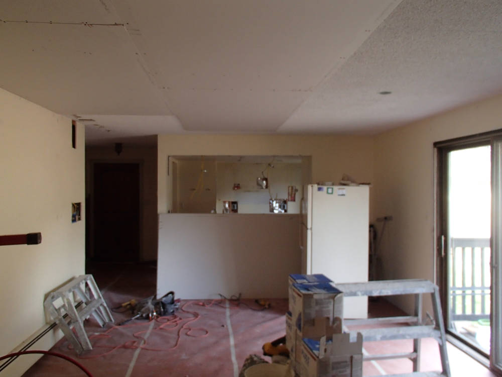 Installing new drywall on top of the popcorn ceiling.